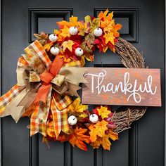 a thanksgiving wreath with the words, thank you and pumpkins hanging on a door