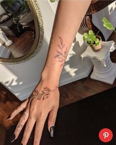 a woman's hand with a flower tattoo on her left arm and the other hand