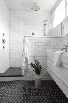 a black and white tiled bathroom with a potted plant in the corner on the floor