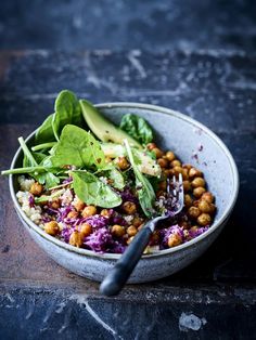 a salad with spinach, chickpeas and avocado in a bowl