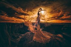 a woman standing on top of a mountain under a cloudy sky