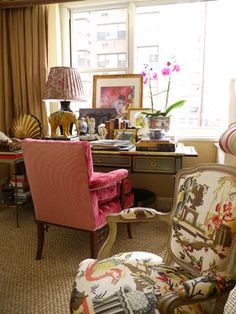 a living room filled with lots of furniture and flowers on top of a window sill