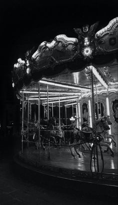 black and white photograph of an old fashioned merry go round at night with people riding on it