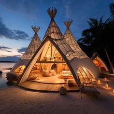 a large white tent sitting on top of a beach next to the ocean at night