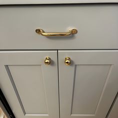 a close up view of the handles on a white cabinet with gold pulls and knobs