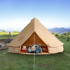 three people are sitting in a tent on the grass