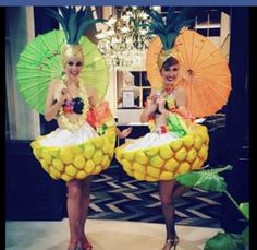 two women dressed in pineapple costumes holding umbrellas and standing next to each other