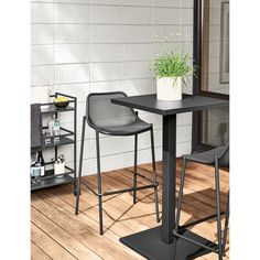 two chairs sitting at a table with a potted plant next to it on a wooden floor