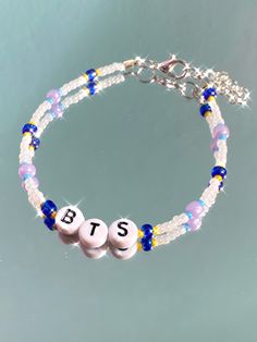 two beads are attached to a bracelet with the word bts written on each bead