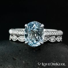 an oval cut aqua blue topazte ring with diamond accents on the band and side stones