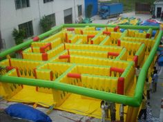 an inflatable maze is set up outside on the ground with people around it