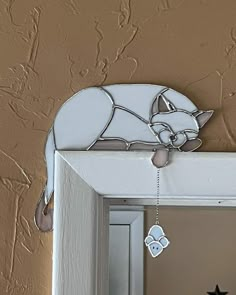 a mirror with a cat decoration hanging from it's side and a star on the other side