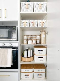 an organized kitchen pantry with white bins and baskets on the shelves, along with other items