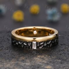 a close up of a wedding ring on a black surface with yellow and white stones