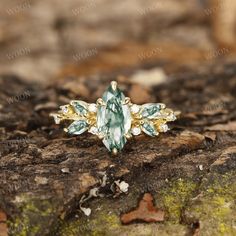 a ring with green and white stones sitting on top of a rock