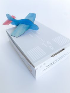 an open box with a paper airplane on the top and bottom part in blue, red, and white