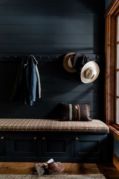 there is a bench with hats on it and two coats hanging up against the wall