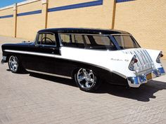 an old black and white car parked in front of a building