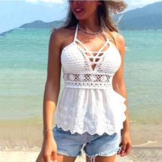 a woman standing on top of a sandy beach next to the ocean wearing a hat