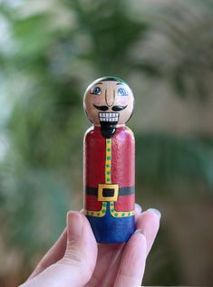 a hand holding a wooden nutcracker with a smiling face