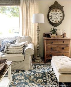 a living room filled with furniture and a large clock on the wall above it's windows