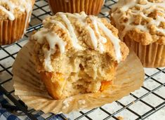 several muffins with white icing sitting on a cooling rack