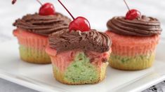 two cupcakes with chocolate frosting and cherries on top are sitting on a white plate