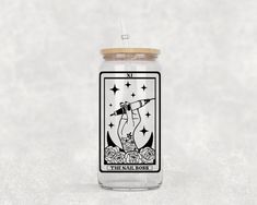 a glass jar with a tarot card on the lid and straw sticking out of it