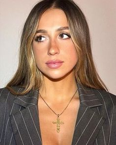 a woman in a suit with a cross necklace