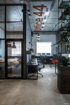 an industrial office with glass walls and steel railings, along with plants on the desk