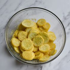 a glass bowl filled with cut up pieces of food on top of a marble counter