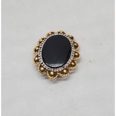 Circa 1980s goldtone oval smooth faux-onyx center with tiny round clear rhinestones surround brooch with security clasp and loop to be worn as a pendant. Measures: 1 3/8 inches long by 1 1/8 inches wide. Condition: Very good; a few of the tiny clear rhinestones have darkened, but they're so small it's not very noticeable. Oval Brooches For Evening, Oval Evening Brooches, Gold Oval Brooch For Evening, Elegant Oval Cabochon Brooch Jewelry, Oval Costume Jewelry Brooch, Formal Round Costume Jewelry Brooches, Formal Costume Jewelry Brooches In Pendant Shape, Formal Costume Jewelry Brooches With Pendant Shape, Formal Costume Jewelry Pendant Brooch