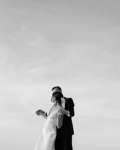 a man and woman standing next to each other on top of a field holding hands