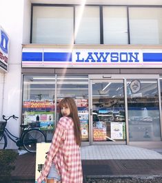 a woman is walking down the sidewalk in front of a store