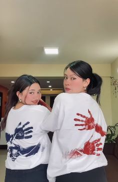 two young women standing next to each other with their hands painted on t - shirts