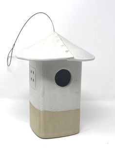 a white bird house with a black hole in the roof