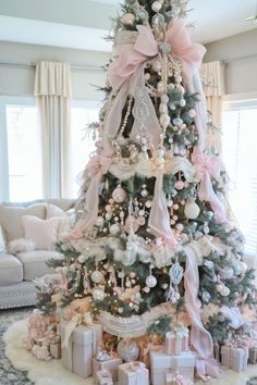 a decorated christmas tree with pink bows and presents on it in a living room area