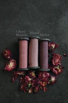 three spools of yarn sitting on top of flowers and the words cherry mauve merlot