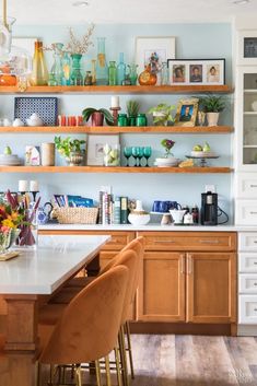 a kitchen filled with lots of wooden shelves covered in vases and flowers on top of it