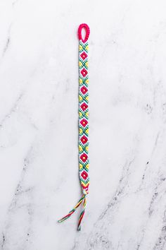 a white marble counter top with a pink and yellow bracelet on it's end