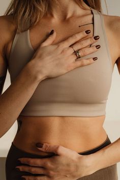 a woman with her hands on her stomach and wearing a tan cropped bra top