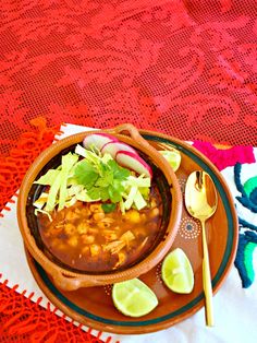 a bowl of soup on a plate with limes and cilantro