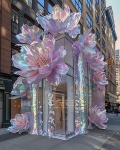 an art installation on the side of a building with large flowers in front of it