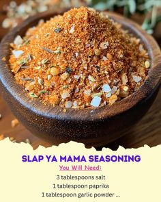 a wooden bowl filled with lots of seasoning on top of a table next to plants