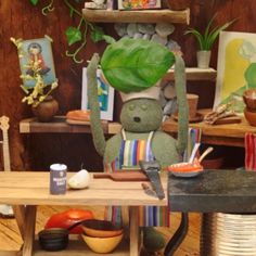 a stuffed animal is sitting on a chair in front of a table with plates and bowls