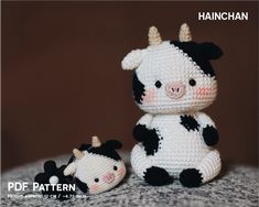 a crocheted cow and its baby are sitting next to each other on a bed