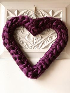 a purple heart hanging on the wall next to a white frame with an ornament