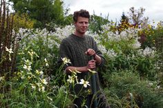 a man standing in the middle of a field with flowers