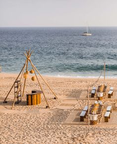 chairs and tables on the beach with an ocean in the background