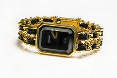 Chanel Premiere Ladies Watch.Vintage Chanel Premier yellow gold plated case, black lacquered dial, ogive-cut onyx cabochon crown, gold plated chain bracelet interwoven with black leather ribbons. Chanel Premiere watch was created back in 1987 by Jacques Helleu, being the first timepiece for Chanel. It’s rectangular case was inspired by the Chanel No.5 perfume bottle stopper and the shape of Place Vendome, located in Paris, France. Gender: Ladies Display: Analog Model: Premiere 1987 Shape: Rectangle. Bracelet Size: 6.5" Luxury Vintage Black Watch Accessories, Luxury Black Timeless Watch Accessories, Luxury Retro Black Watch Accessories, Luxury Black Jewelry With Rectangular Dial, Luxury Vintage Black Watches, Luxury Vintage Black Watch, Luxury Timeless Black Watch Accessories, Luxury Black Classic Jewelry And Watches, Womens Chanel Watch